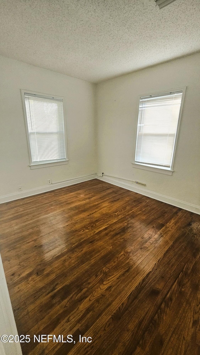 4916 Dundee Rd, Jacksonville, FL 32210 - empty room with dark wood finished floors, plenty of natural light, and a textured ceiling