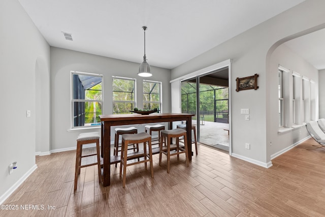 dining area with visible vents, arched walkways, light wood-style flooring, and baseboards