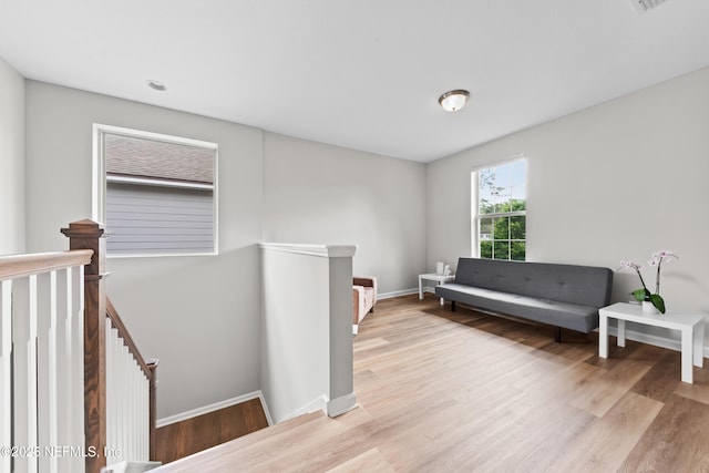 living area with light wood-style floors, baseboards, and an upstairs landing