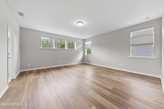 empty room featuring baseboards, visible vents, a healthy amount of sunlight, and light wood-type flooring