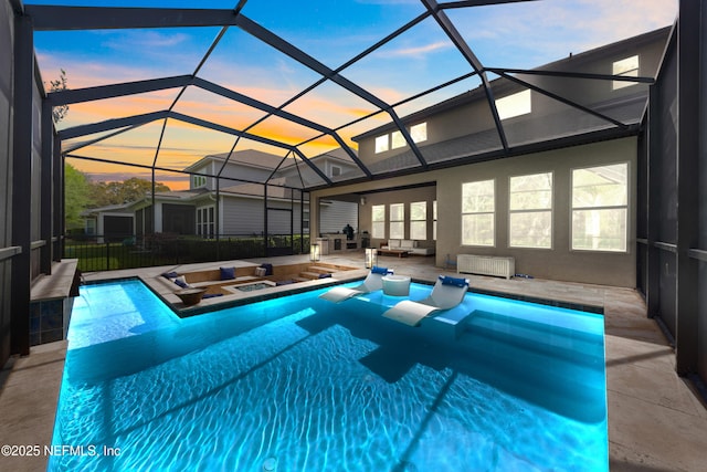 pool at dusk featuring a jacuzzi, a fenced in pool, an outdoor living space, a lanai, and a patio