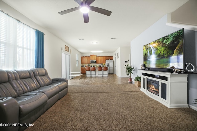 living area with light carpet, ceiling fan, and visible vents