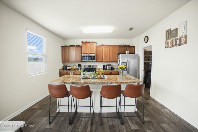 kitchen featuring appliances with stainless steel finishes, a breakfast bar area, dark wood-style floors, and visible vents