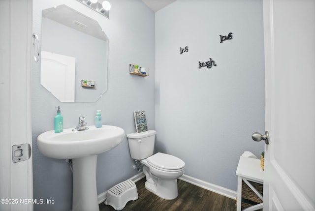 half bath featuring toilet, baseboards, and wood finished floors