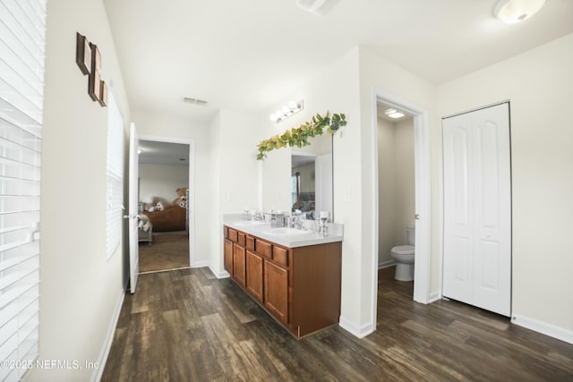 full bathroom with toilet, wood finished floors, a sink, and connected bathroom