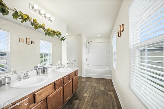 bathroom featuring double vanity, bathtub / shower combination, a sink, and wood finished floors