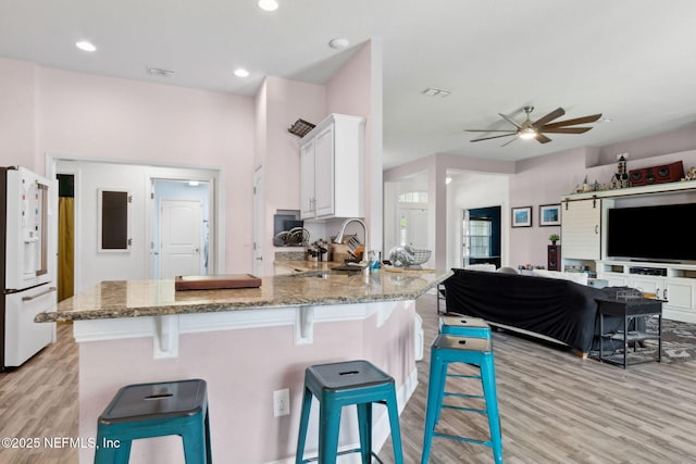 11975 Smith Pointe Ct, Jacksonville, FL 32218 - kitchen with light stone countertops, white refrigerator with ice dispenser, light wood-type flooring, white cabinetry, and a sink