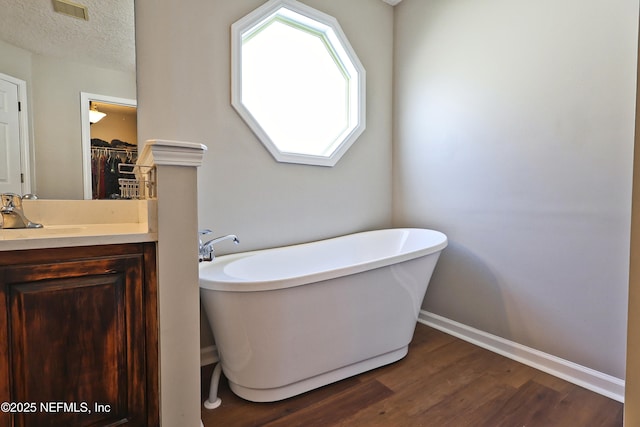 3038 Majestic Oaks Ln, Green Cove Springs, FL 32043 - bathroom featuring a textured ceiling, a freestanding tub, vanity, visible vents, and wood finished floors