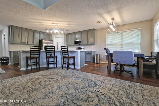 3038 Majestic Oaks Ln, Green Cove Springs, FL 32043 - kitchen featuring dark wood-style floors, light countertops, gray cabinetry, a breakfast bar area, and appliances with stainless steel finishes