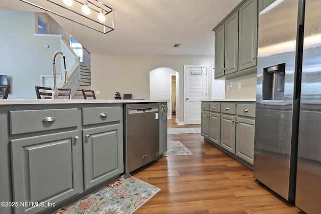 3038 Majestic Oaks Ln, Green Cove Springs, FL 32043 - kitchen with arched walkways, appliances with stainless steel finishes, a textured ceiling, dark wood finished floors, and gray cabinets