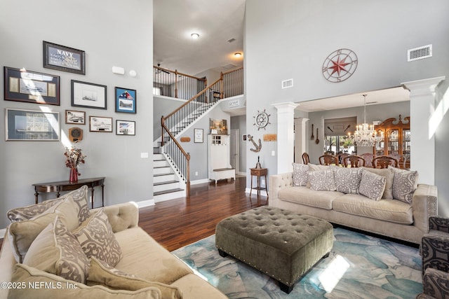 11725 Paddock Gates Dr, Jacksonville, FL 32223 - living area featuring decorative columns, a towering ceiling, a chandelier, stairs, and wood finished floors