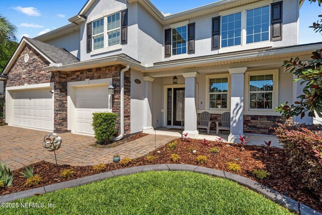 11725 Paddock Gates Dr, Jacksonville, FL 32223 - view of front facade featuring stucco siding, a porch, stone siding, and decorative driveway