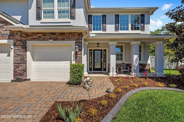 11725 Paddock Gates Dr, Jacksonville, FL 32223 - view of front of property with stone siding, stucco siding, a porch, an attached garage, and decorative driveway