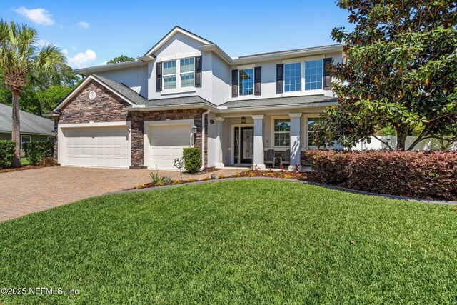 11725 Paddock Gates Dr, Jacksonville, FL 32223 - view of front of home with stucco siding, decorative driveway, a front lawn, a porch, and stone siding