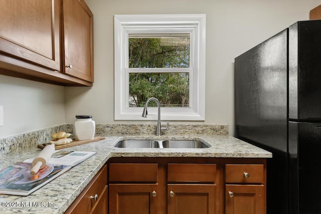10625 Dodd Rd, Jacksonville, FL 32218 - kitchen featuring brown cabinets, freestanding refrigerator, a sink, and light stone countertops