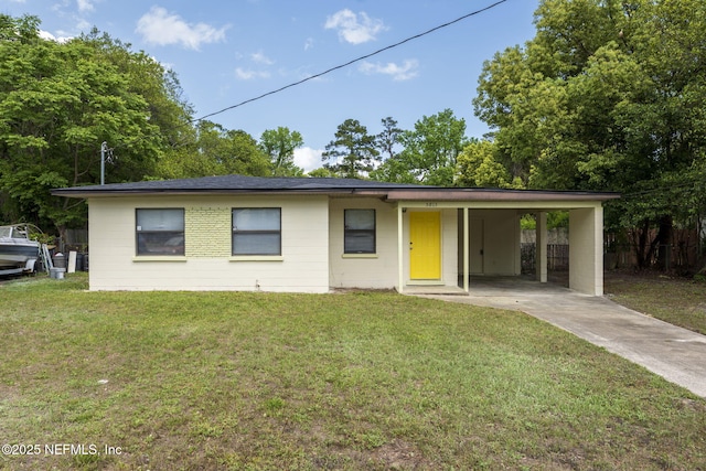 ranch-style home featuring concrete driveway, an attached carport, concrete block siding, and a front yard