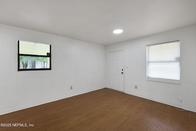 unfurnished room with baseboards and dark wood-style flooring