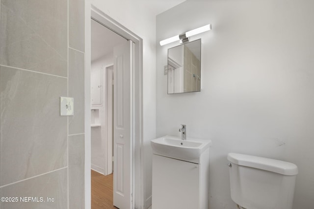 bathroom with toilet, vanity, and wood finished floors