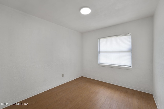 unfurnished room with baseboards and dark wood-style floors