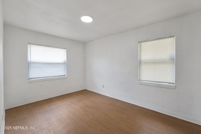 spare room with baseboards and wood finished floors