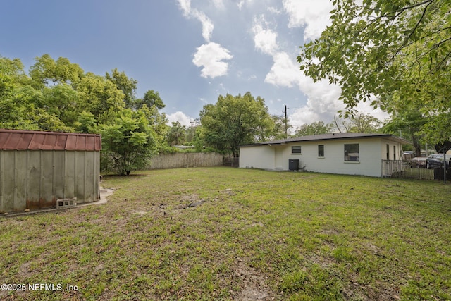 view of yard featuring a fenced backyard, central AC unit, an outbuilding, and a storage unit
