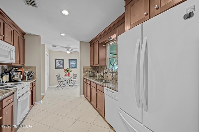 706 Montego Rd E, Jacksonville, FL 32216 - kitchen with visible vents, light tile patterned floors, a sink, white appliances, and backsplash