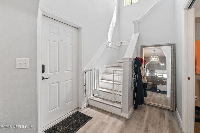 entryway featuring baseboards, wood finished floors, a high ceiling, and stairs