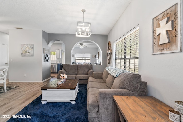 living area with wood finished floors, visible vents, arched walkways, baseboards, and a notable chandelier