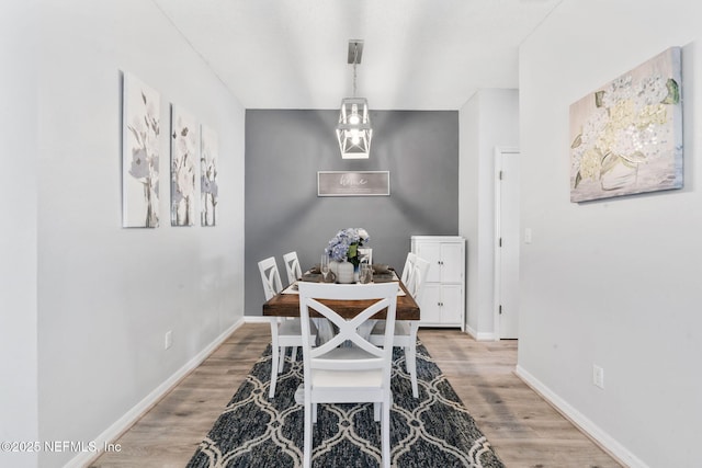 dining space with light wood-type flooring and baseboards