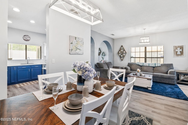 dining room with light wood-type flooring, arched walkways, a notable chandelier, visible vents, and recessed lighting