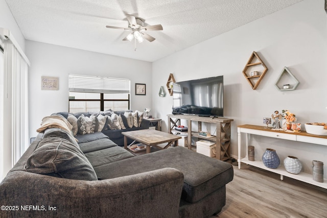 living area featuring wood finished floors, a textured ceiling, and a ceiling fan