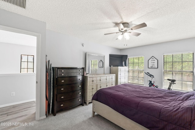 bedroom featuring a textured ceiling, visible vents, a ceiling fan, and baseboards