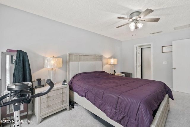 carpeted bedroom featuring ceiling fan, a textured ceiling, and visible vents