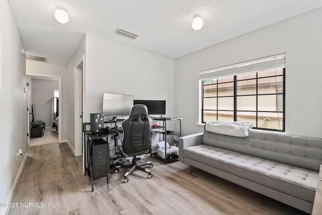 office area featuring baseboards, visible vents, wood finished floors, and a textured ceiling