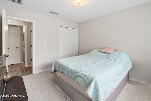 carpeted bedroom featuring a closet, visible vents, and baseboards