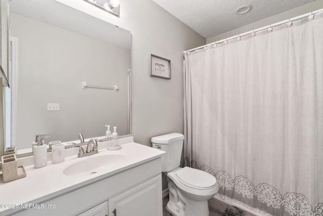 full bath with a textured ceiling, toilet, and vanity