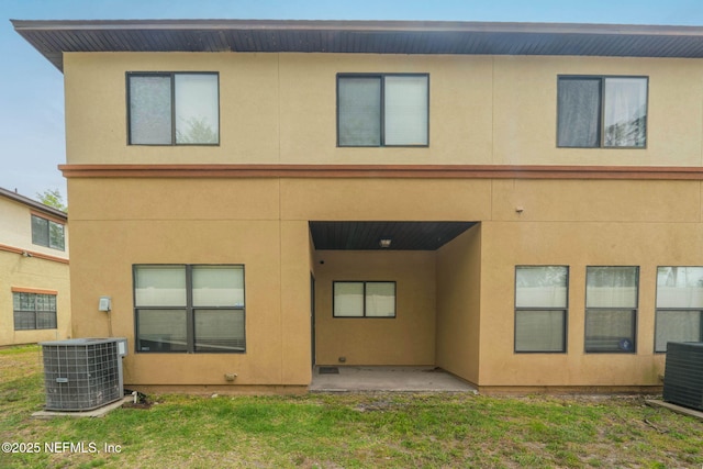 back of house with stucco siding, a patio area, a yard, and central AC unit