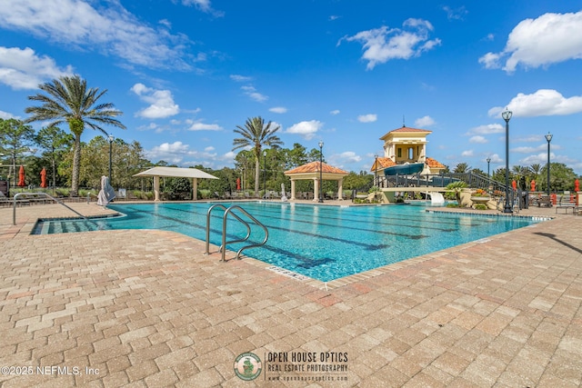 community pool featuring a water slide, a gazebo, and a patio area