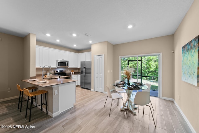 2627 Sandy Dune Dr, Jacksonville, FL 32233 - kitchen with baseboards, a sink, a peninsula, light wood finished floors, and stainless steel appliances