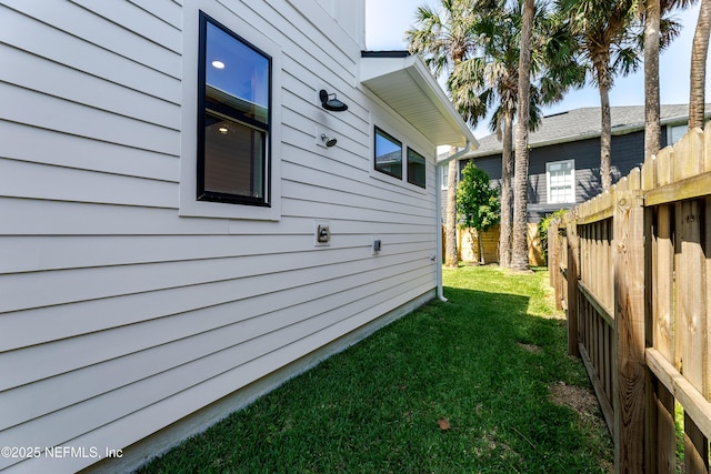 view of side of home featuring a yard and fence