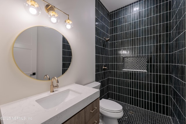 full bath featuring vanity, a tile shower, and toilet
