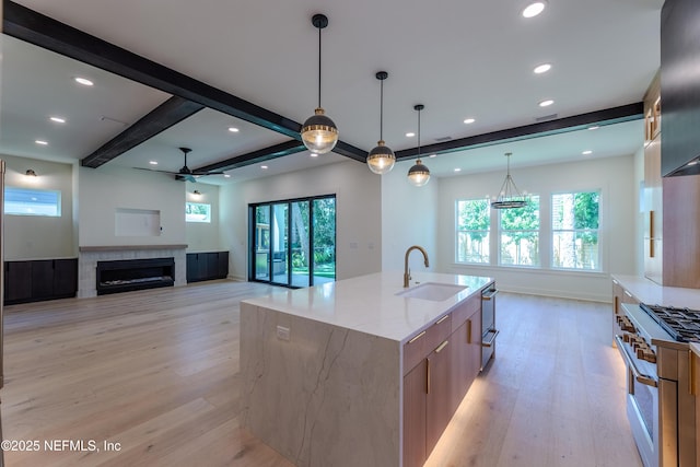 kitchen with high end range, modern cabinets, a tile fireplace, a sink, and light wood finished floors