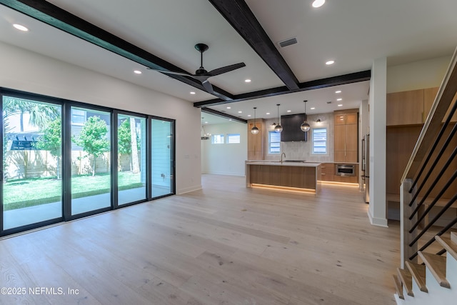 unfurnished living room with baseboards, stairway, beamed ceiling, ceiling fan, and light wood finished floors