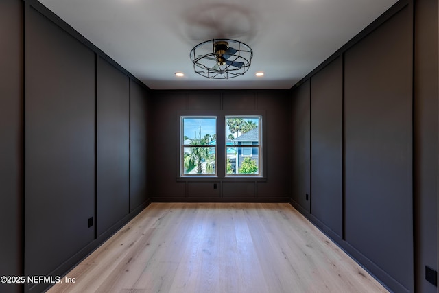 empty room with light wood-style flooring, a decorative wall, a ceiling fan, and recessed lighting