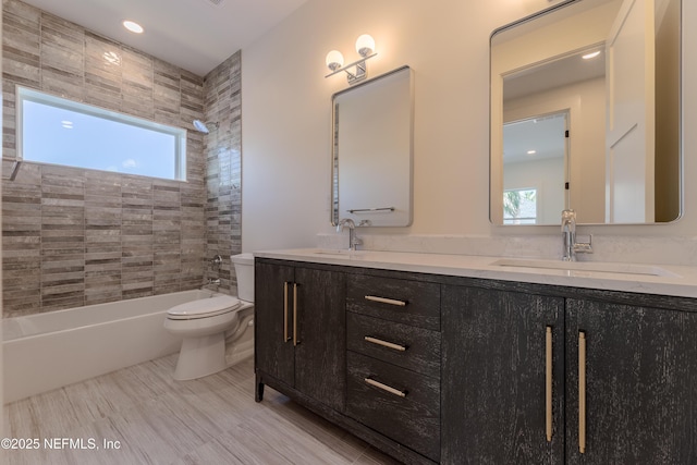 bathroom featuring a sink, washtub / shower combination, toilet, and double vanity