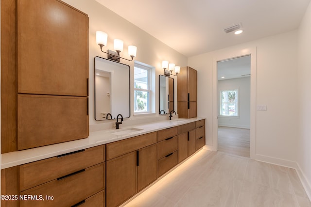 full bath featuring a sink, visible vents, baseboards, and double vanity