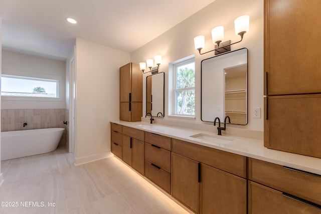 full bathroom featuring plenty of natural light, double vanity, and a sink