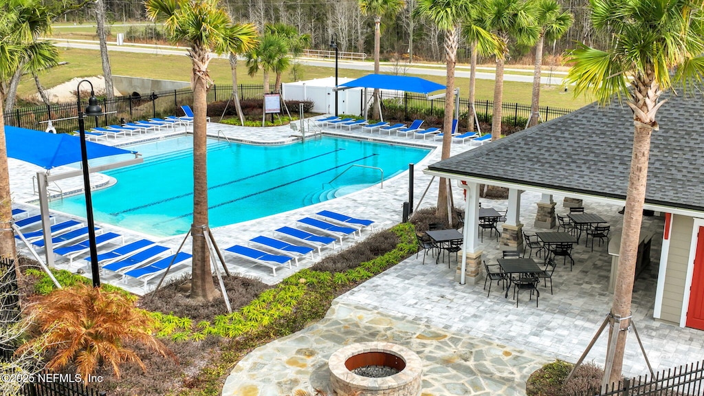 community pool featuring a patio area, a fenced backyard, and an outdoor fire pit