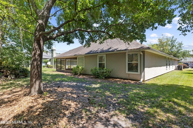 view of property exterior featuring a yard, a sunroom, and roof with shingles