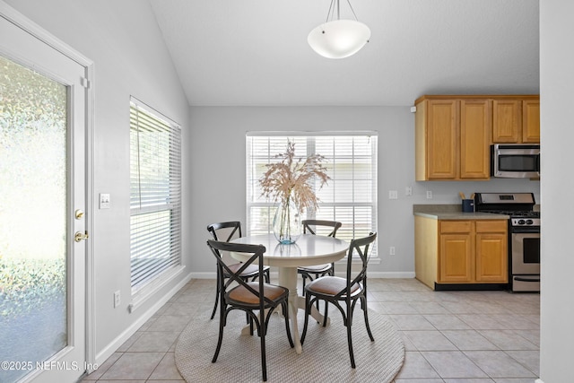 dining area with lofted ceiling, baseboards, and light tile patterned floors